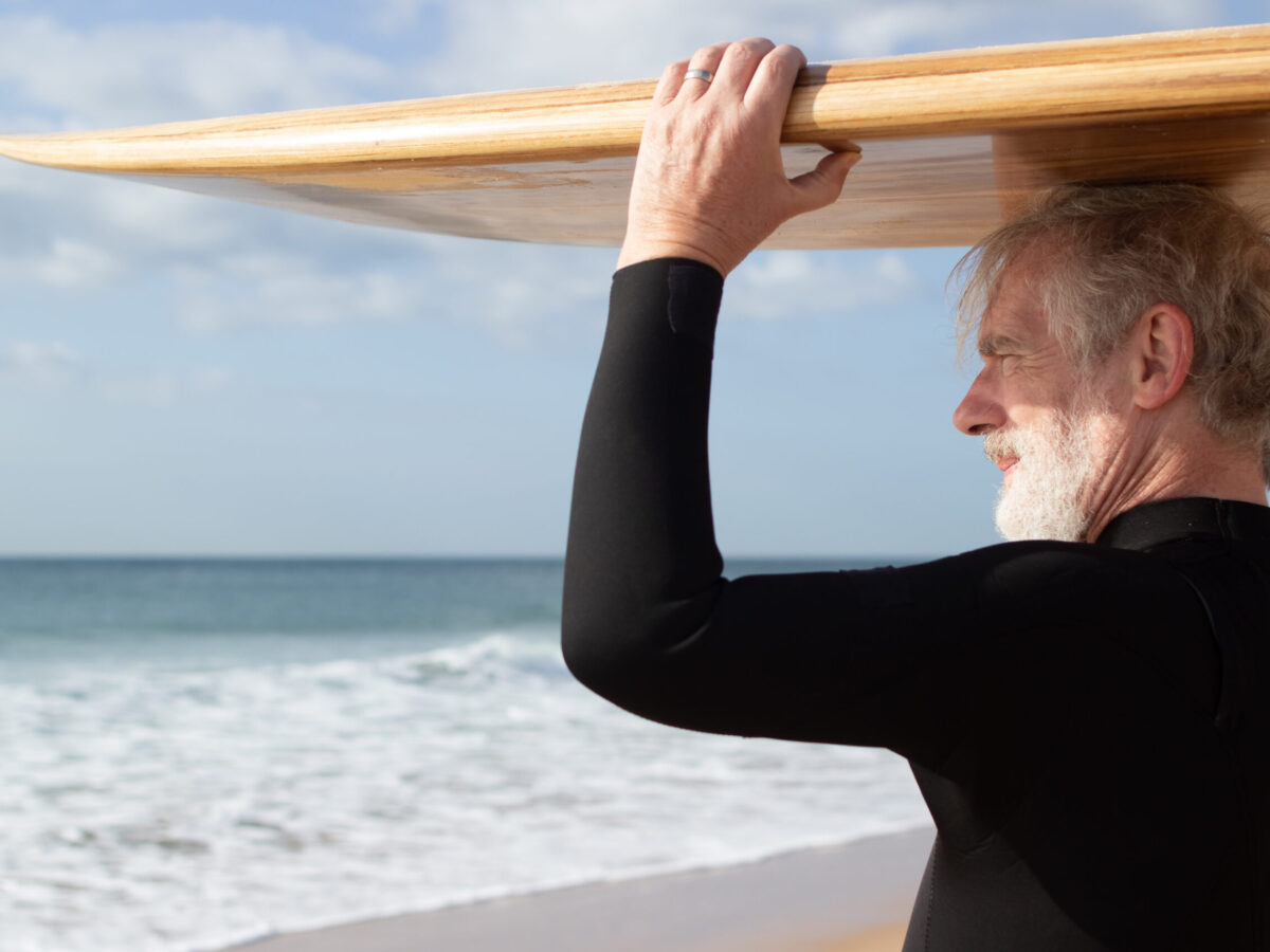 homme senior tenant un paddle sur la tête en bord de mer à toulon