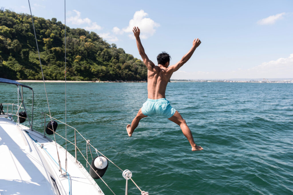 homme sautant du pont d'un catamaran durant une fête d'anniversaire